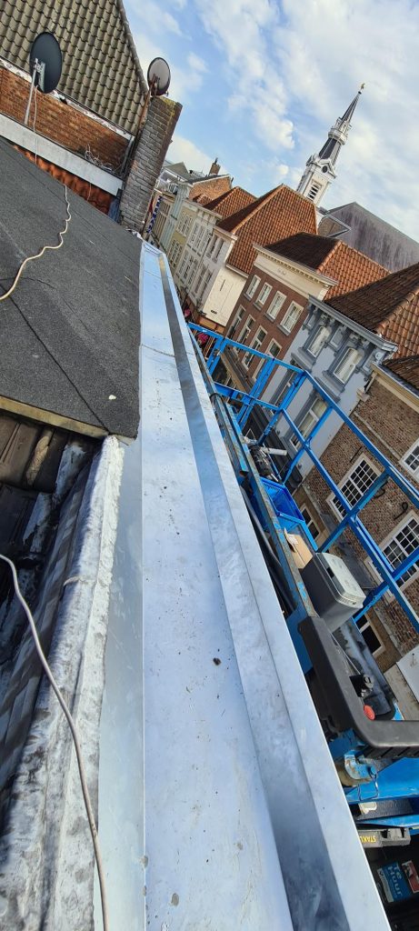 Dakdekker soldeert nieuwe zinken tussengoot tussen pannendak en dakraam in Goes